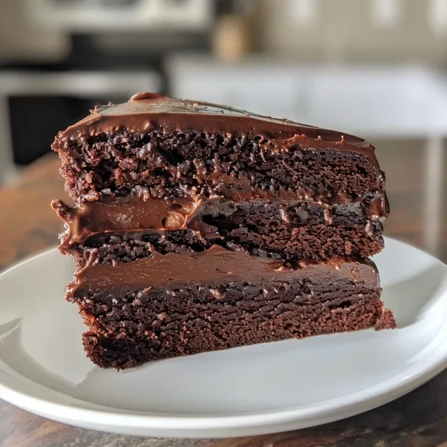 Juicy vegan chocolate cake with a glossy frosting, presented from a side angle.