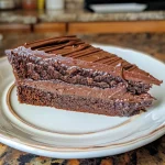 Close-up side view of a decadent gluten-free chocolate cake with rich frosting.