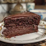 A rich, gluten-free chocolate cake with a glossy frosting, displayed from a side angle.