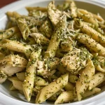 Creamy Pesto Chicken Pasta served in a white bowl with fresh basil garnish.
