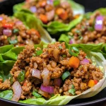 Close-up view of juicy ground turkey lettuce wraps garnished with diced vegetables.