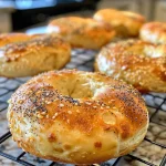 A close-up side view of a golden-brown high-protein cottage cheese bagel with sesame and poppy seeds on top.