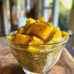 Close-up view of a creamy mango coconut chia pudding topped with fresh mango slices and shredded coconut.