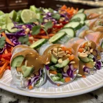 Close-up of a vibrant Spring Roll Salad topped with creamy peanut sauce and various fresh vegetables.