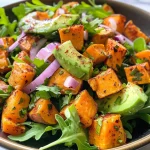 Close-up of a vibrant Sweet Potato & Avocado Salad with colorful ingredients.