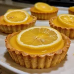 A close-up side view of a Vegan Mini Lemon Tart showcasing its creamy filling and crumbly crust.