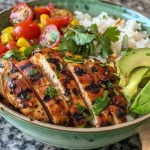 Close-up of Honey Lime Cilantro Chicken served over rice with colorful toppings.