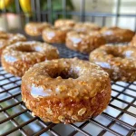 Close-up view of baked banana oat doughnuts with a golden-brown glaze.