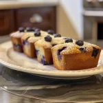 Close-up view of moist lemon blueberry mini loaves with glistening blueberries.