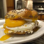 A side view of a high protein breakfast bagel with eggs and cheese.