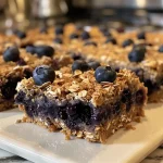 Close-up of a blue and golden baked Blueberry Oat Square with a crumbly texture.