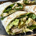 Close-up side view of a Chicken Avocado Wrap filled with chicken, avocado, and greens.