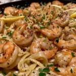 Close-up of a fork twirling lemon garlic butter shrimp pasta with fresh parsley on top.