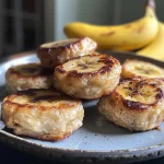 Close-up of fluffy pancake bites topped with banana slices on a plate.