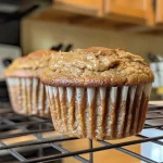 Close-up view of golden-brown peanut butter banana muffins on a plate.