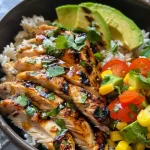 A close-up side view of a vibrant grilled chicken summer rice bowl, featuring colorful ingredients.
