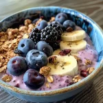 A side view of a colorful yogurt bowl filled with blueberries and bananas.