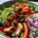 Close-up view of a vibrant BBQ chicken bowl with colorful grilled vegetables and sliced sweet potatoes.