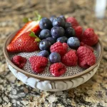Close-up of a creamy berry chia seed pudding in a glass bowl, topped with fresh berries.