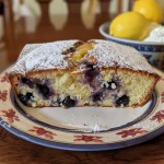 A slice of blueberry lemon loaf showcasing vibrant blueberries and a golden crust.