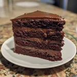 Close-up side view of a moist chocolate layer cake with peanut butter frosting and chocolate ganache.