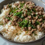 A close-up view of a Garlic Butter Beef Bowl featuring fluffy rice, ground beef, and melted cheese.