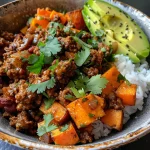 A vibrant bowl of ground beef topped with hot honey, served with sweet potatoes and avocado.