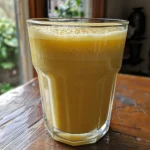 Close-up view of a vibrant green juice in a clear glass, showing ingredients like green tea extract and African mango.