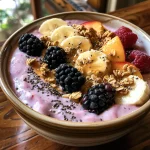 Close-up view of a vibrant Peach Smoothie Bowl topped with fruits and granola.