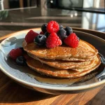 Fluffy protein pancakes stacked high, topped with fresh mixed berries.