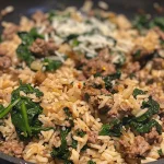 Close-up view of a skillet filled with beef, spinach, and rice, garnished with Parmesan cheese.
