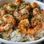 A close-up side view of a spicy garlic butter shrimp rice bowl, showcasing juicy shrimp, fluffy white rice, and fresh garnishes.