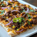 Close-up view of a Tex-Mex BBQ beef flatbread topped with melted cheese, red onions, and jalapeños.
