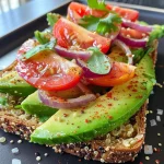 ['Close-up view of avocado toast on quinoa bread topped with cherry tomatoes and cress.', 'Side view of a delicious avocado toast on quinoa bread garnished with red onion and herbs.', 'Quinoa bread slice topped with smashed avocado, cherry tomatoes, and fresh cress, captured up close.', 'Textured quinoa bread with creamy avocado spread and colorful toppings, showcased in a close-up shot.']