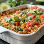 ['A close-up side view of a vibrant Chickpea and Rice Enchilada Bake with melted cheese on top.', 'A colorful Chickpea Rice Enchilada Bake, featuring layers of ingredients and garnishes.', 'An appetizing side view of a baked dish filled with chickpeas, rice, and enchilada sauce, topped with fresh cilantro.', 'A detailed shot of a Chickpea and Rice Enchilada Bake, showcasing its hearty texture and colorful toppings.']