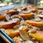 ['Close-up of a baked peach cobbler topped with oats and almonds.', 'Side view of a high-protein peach cobbler with sliced peaches and yogurt.', 'Juicy peach cobbler with a golden crust and almond topping in a bowl.', 'Freshly made peach cobbler showcasing sliced peaches and dairy toppings.']