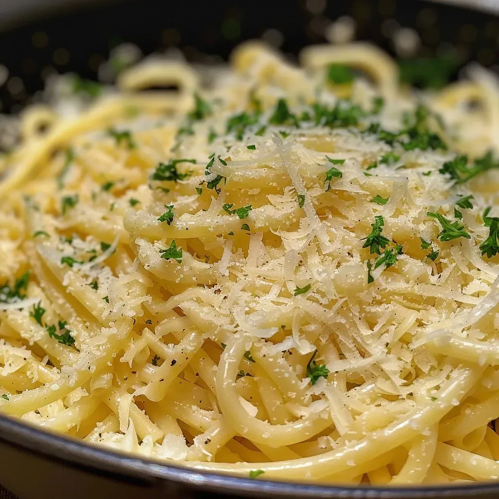 Close-up of creamy garlic pasta with melted cheese and herbs.