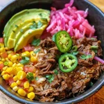 ['Close-up view of a Beef Barbacoa Bowl with colorful toppings.', 'Side angle of a delicious Beef Barbacoa Bowl featuring sliced avocado and corn.', 'Image of a savory Beef Barbacoa Bowl garnished with jalapeños and cilantro.', 'Juicy Beef Barbacoa Bowl with rice, avocado, and pickled onions in focus.']