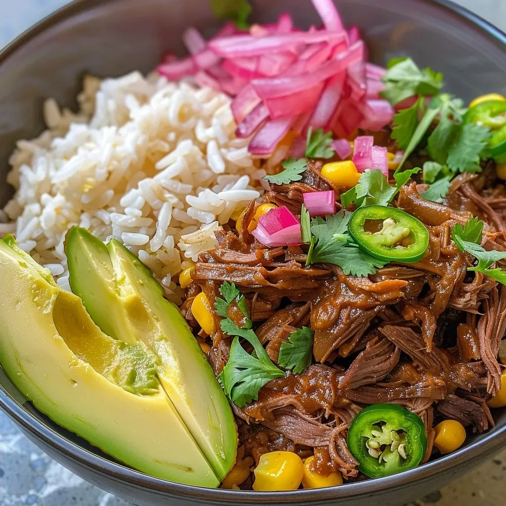 ['Close-up view of a Beef Barbacoa Bowl with colorful toppings.', 'Side angle of a delicious Beef Barbacoa Bowl featuring sliced avocado and corn.', 'Image of a savory Beef Barbacoa Bowl garnished with jalapeños and cilantro.', 'Juicy Beef Barbacoa Bowl with rice, avocado, and pickled onions in focus.']