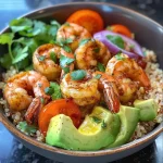 ['Close-up of a quinoa bowl topped with shrimp, cherry tomatoes, and avocado.', 'Side view of a colorful quinoa bowl featuring shrimp, diced avocado, and red onion.', 'Delicious quinoa dish with large shrimp, garnished with fresh cilantro and lemon slices.', 'Vibrant quinoa bowl showcasing shrimp, halved cherry tomatoes, and thinly sliced red onion.']