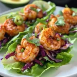 ['Close-up of shrimp taco lettuce wraps with vibrant slaw and creamy sauce.', 'Juicy shrimp tucked in lettuce leaves, garnished with colorful toppings.', 'Tasty shrimp tacos served in crisp lettuce, featuring fresh vegetables and sauce.', 'Mouthwatering shrimp lettuce wraps showcasing a variety of vibrant ingredients.']