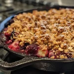 ['Close-up side view of a baked Skillet Berry Crisp with a golden topping and colorful berries.', 'Juicy Skillet Berry Crisp in a cast iron skillet, showcasing a crumbly topping and fresh berries.', 'Richly colored assortment of berries topped with a crispy layer in a skillet.', 'Delicious Skillet Berry Crisp displayed in a skillet, highlighting its baked texture and vibrant fruit.']