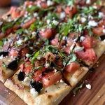 ['Close-up view of a slice of flatbread topped with watermelon jam, feta cheese, and arugula.', 'Side view of a delicious flatbread with melted cheeses and colorful watermelon jam.', 'A juicy flatbread topped with crumbled feta, mozzarella, and fresh diced watermelon.', 'A vibrant slice of flatbread showcasing watermelon jam, cheese, and a drizzle of balsamic glaze.']