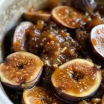 ['Close-up of a jar of homemade fig butter with a spoon beside it.', 'Side view of a creamy Crockpot fig butter in a glass jar, topped with spices.', 'A textural view of smooth fig butter with chopped figs scattered around.', 'Rich, dark brown fig butter in a bowl, garnished with a lemon slice.']