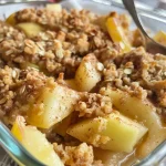 ['Close-up view of a healthy high protein apple crisp topped with oats and nuts.', 'Side view of a delicious apple crisp with visible apple chunks and a golden crumble topping.', 'Juicy apple crisp garnished with cinnamon and nut toppings, presented on a plate.', 'A bowl filled with healthy apple crisp featuring chopped apples and a crunchy oat topping.']