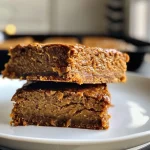 ['A close-up side view of healthy pumpkin bars on a plate, showcasing their moist texture.', 'Juicy and delicious healthy pumpkin bars displayed attractively, highlighting their pumpkin color and toppings.', 'Side view of well-portioned healthy pumpkin bars, featuring rich pumpkin hues and creamy topping.', 'A detailed close-up of pumpkin bars with toppings, emphasizing their healthy ingredients.']