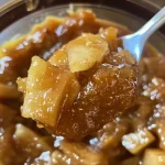 ['A close-up view of a jar filled with golden-brown salted caramel apple butter.', 'A side view of luscious salted caramel apple butter in a glass jar with a wooden spoon.', 'An inviting scene showcasing a jar of salted caramel apple butter against a rustic background.', 'A delectable close-up of salted caramel apple butter, highlighting its smooth, glossy texture.']