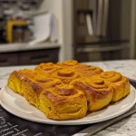 ['Close-up view of freshly baked soft pumpkin rolls, showcasing their golden-brown color and fluffy texture.', 'Side angle photo of warm pumpkin rolls with a soft, pillowy appearance, highlighting their inviting color.', 'Juicy pumpkin rolls arranged neatly, emphasizing their moistness and soft edges in a home kitchen setting.', 'Detailed shot of pumpkin rolls, capturing their fluffy texture and rich color, perfect for a fall dessert.']