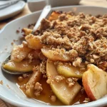 ['Close-up view of a freshly baked Spiced Apple Crumble with a golden crisp topping.', 'Side view of a delicious Spiced Apple Crumble, highlighting its juicy apple filling and crumbly texture.', 'Juicy Spiced Apple Crumble in a baking dish, showcasing its golden brown topping and apple slices.', 'Delicious Spiced Apple Crumble with a flaky crust, filled with cinnamon-spiced apple chunks and raisins.']