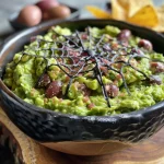 ['Close-up view of guacamole with a decorative spider web made of sour cream and olives.', 'Juicy guacamole with a spooky spider web design created using sour cream and olive pieces.', 'Side view of a creamy guacamole bowl decorated with a spider web pattern from sour cream and olives.', 'A vibrant serving of guacamole featuring a spooky web design made of sour cream and olives.']